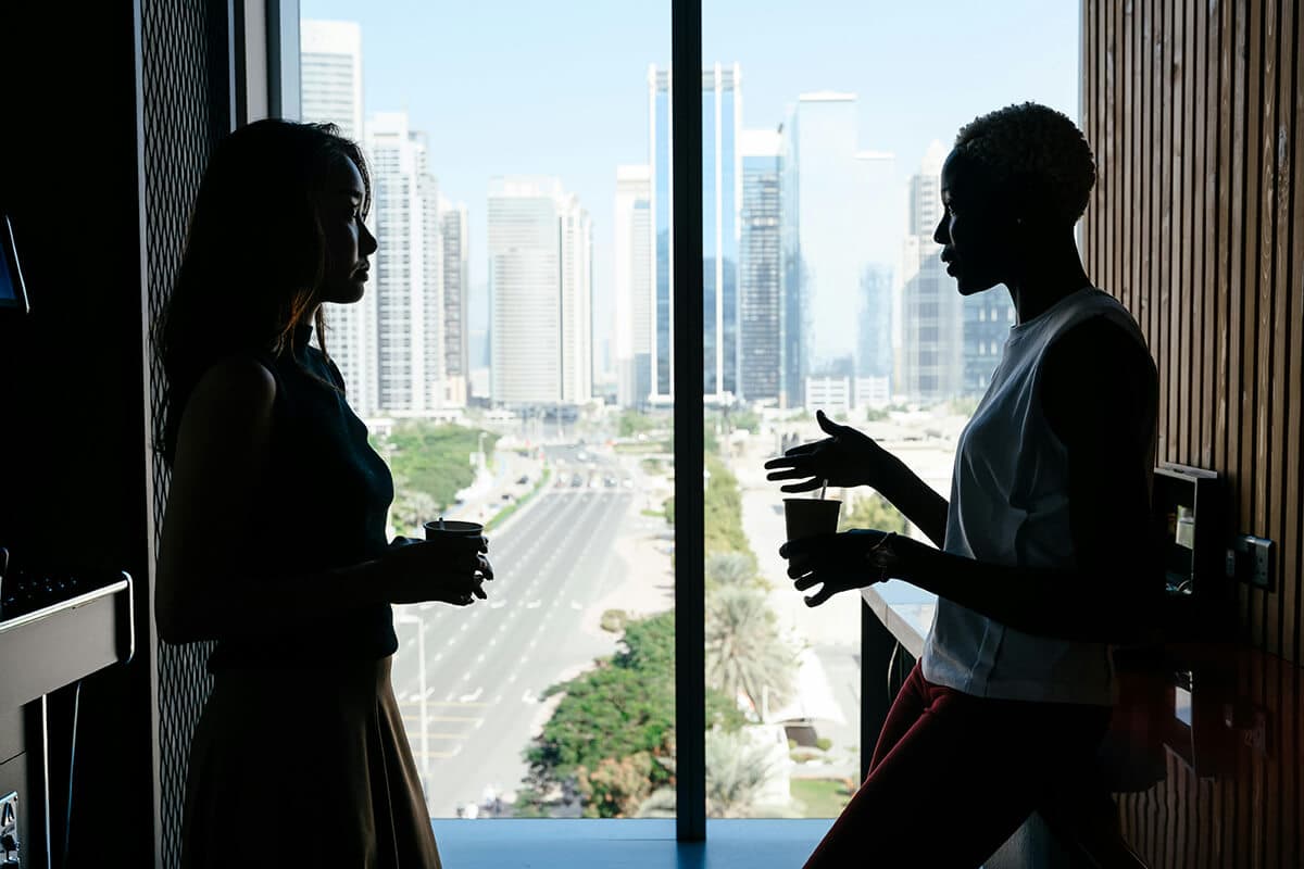 One woman employee meeting with another woman employee in an office kitchen to guide the mentoring relationship forward.