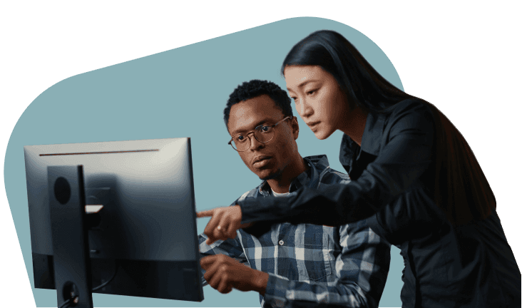 A woman points at a computer screen while a colleague in glasses looks on