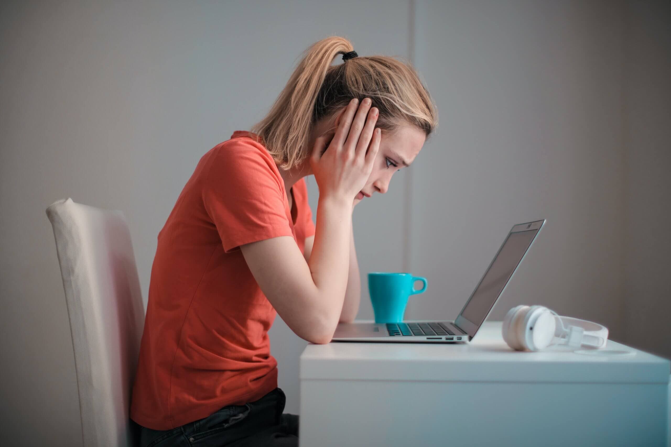 woman at desk with hands covering her ears