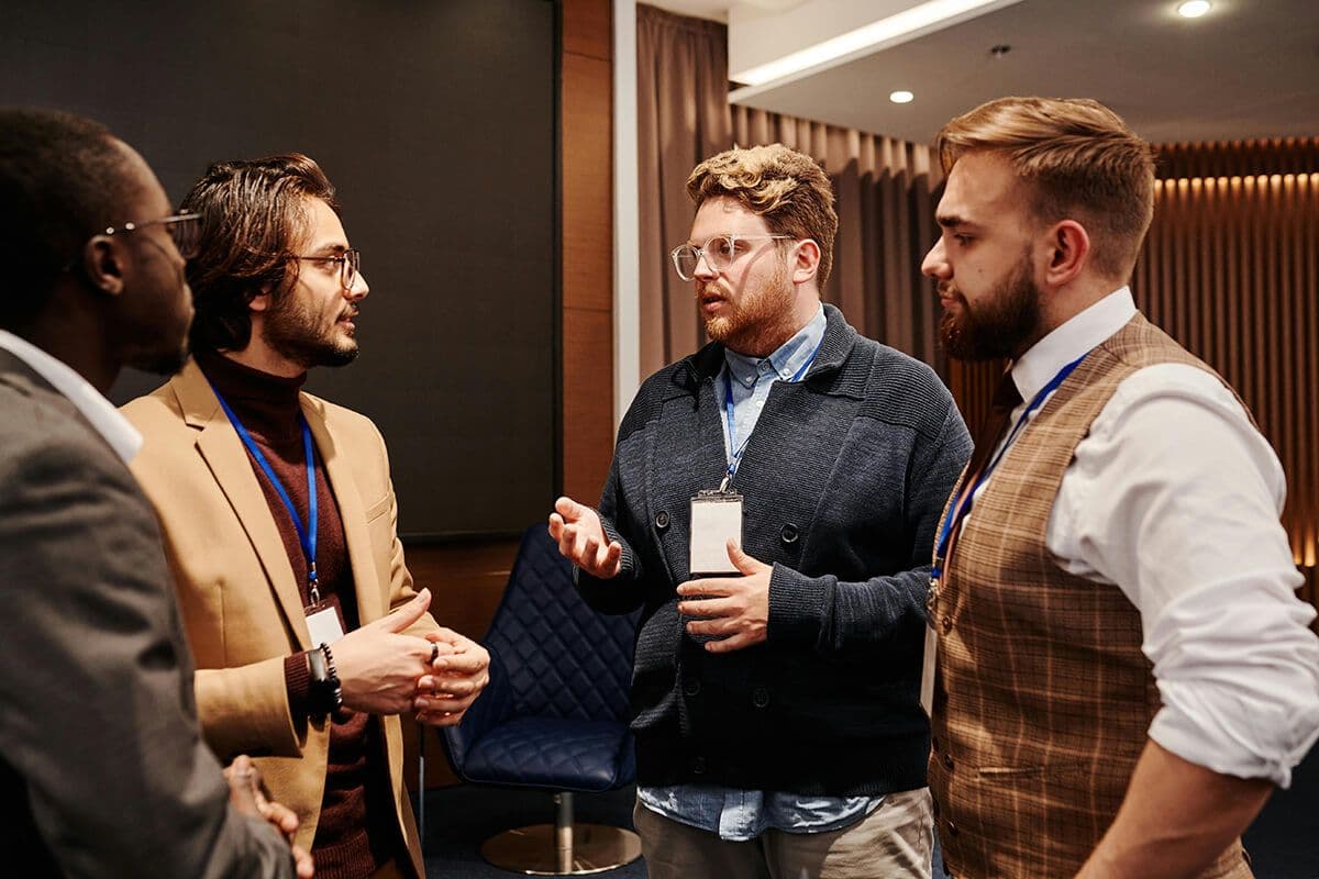 male colleagues standing around in a circle at a conference discussing management skills