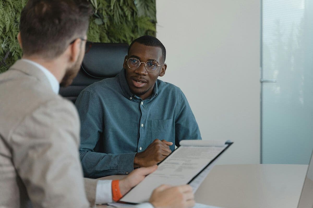 Man sitting in a conference room with colleague while they look at upskilling employees