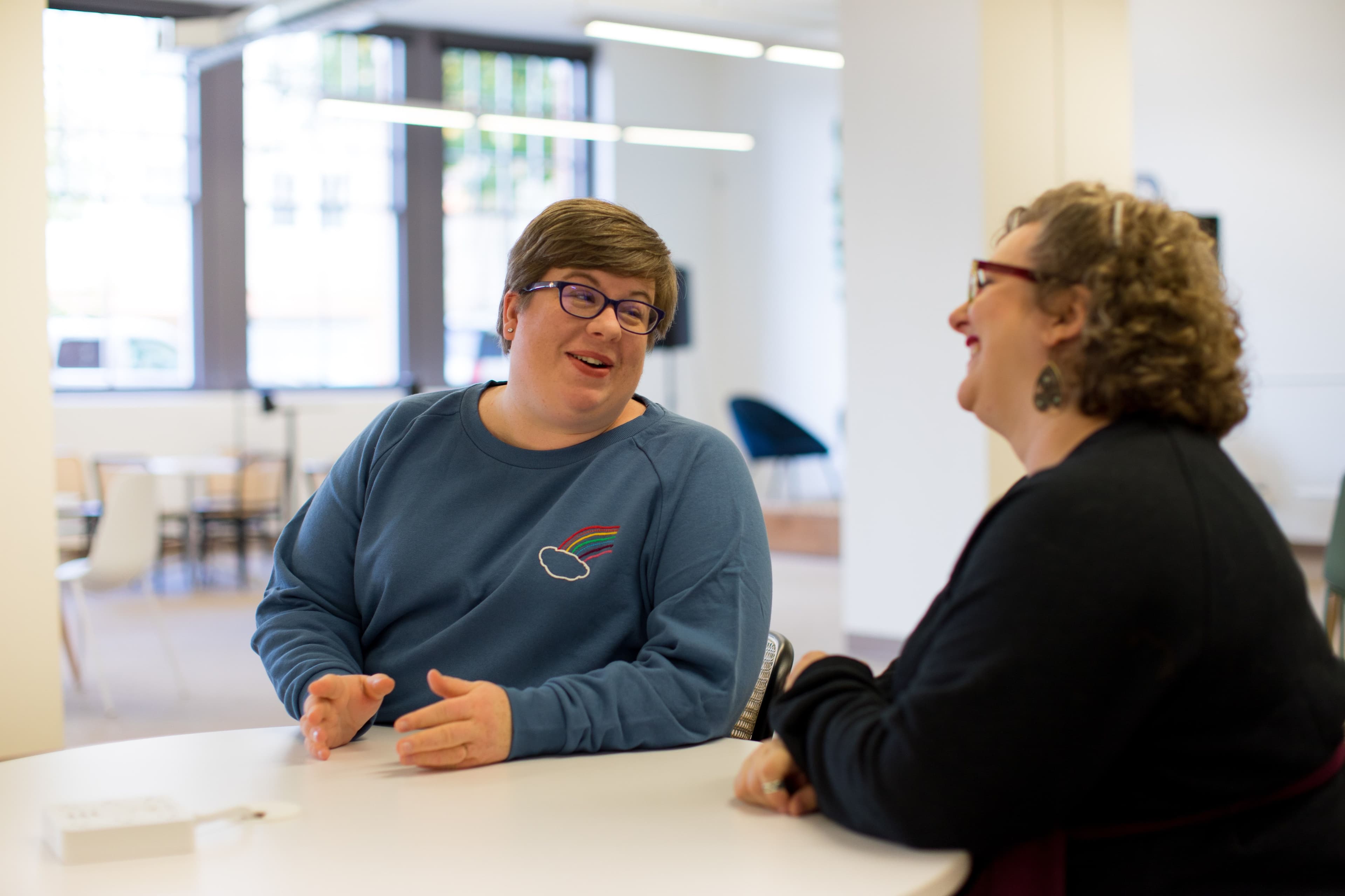 A non-binary person asking their mentor questions about their professional experience