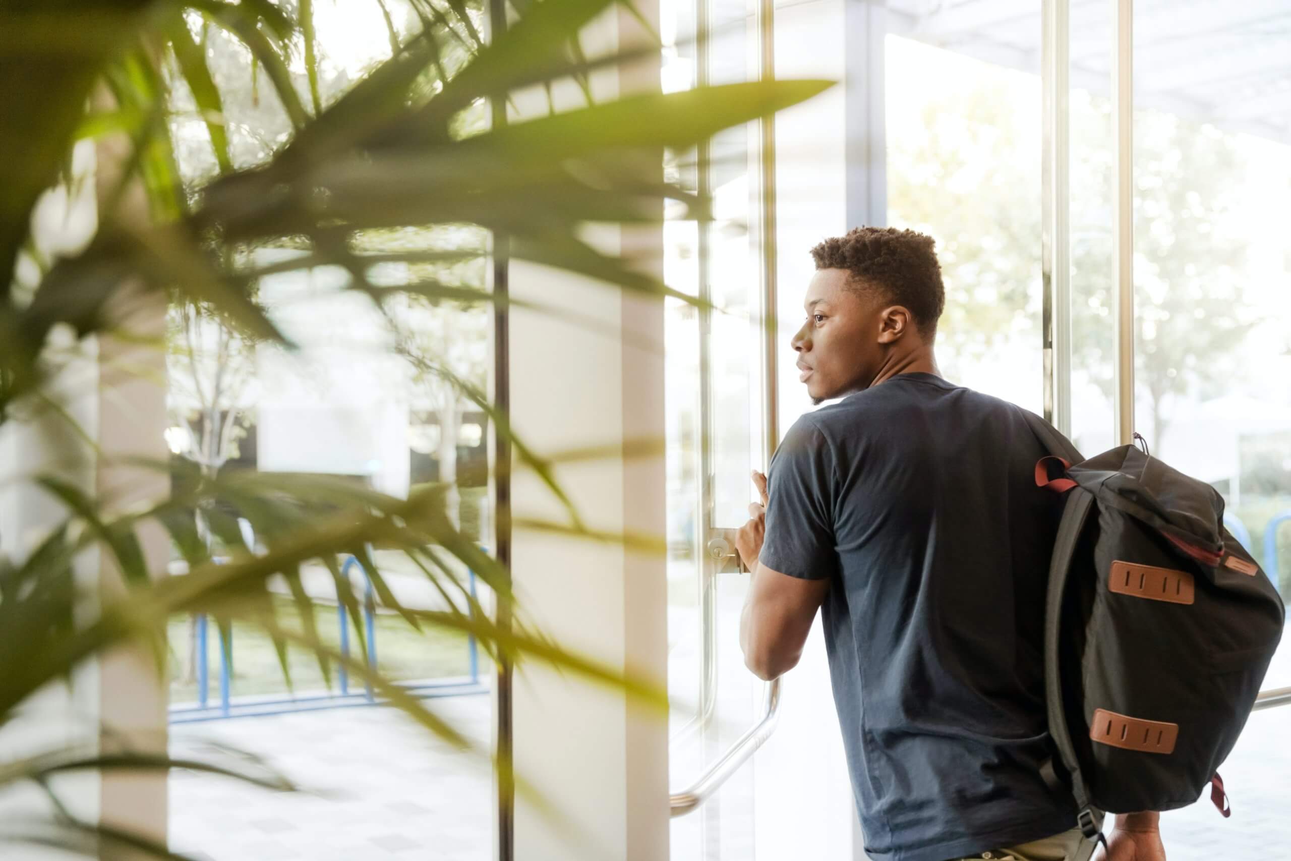 black male student with backpack leaving building