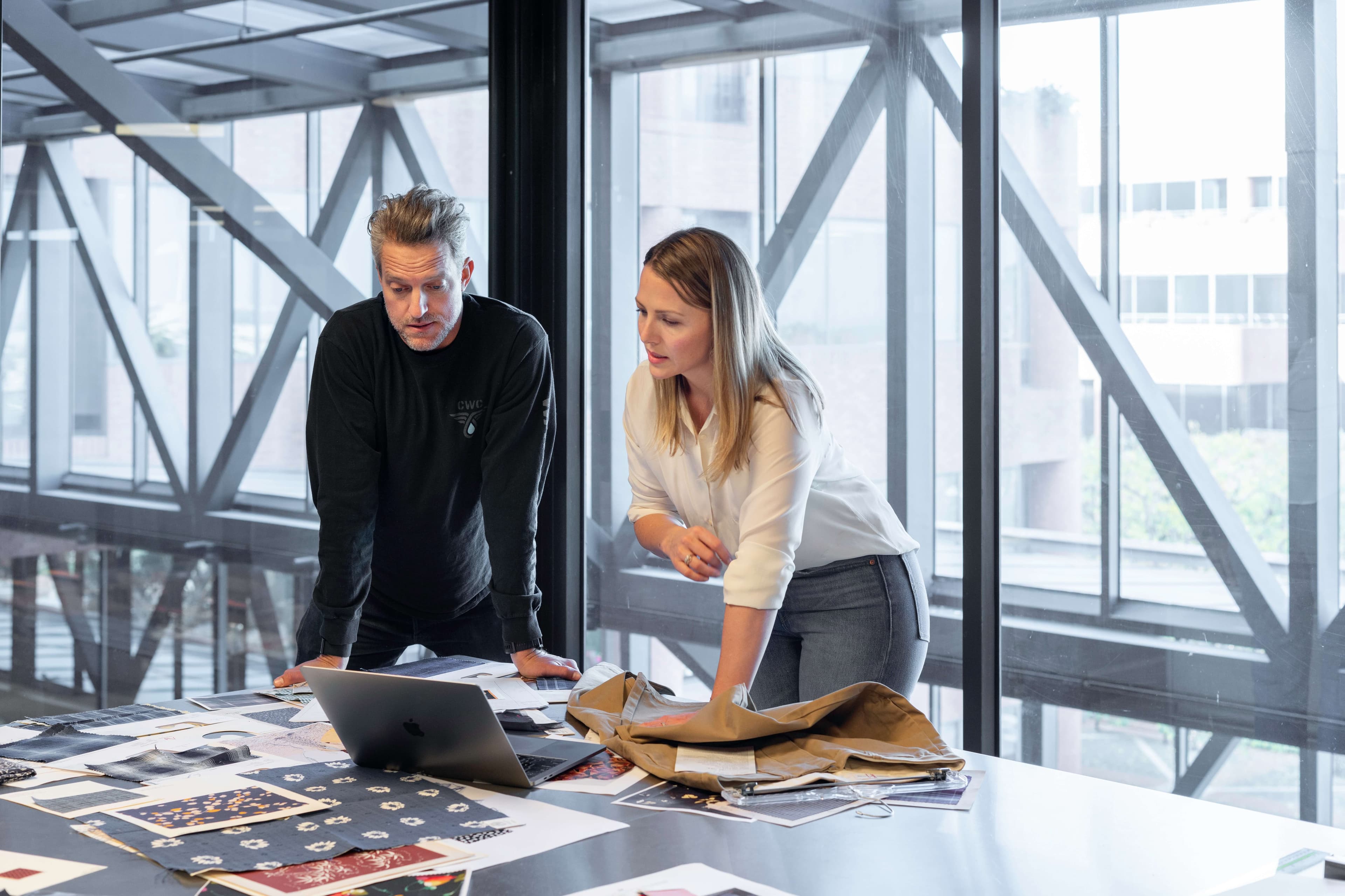 reverse mentoring session with older male employee and younger woman employee in an office at a table
