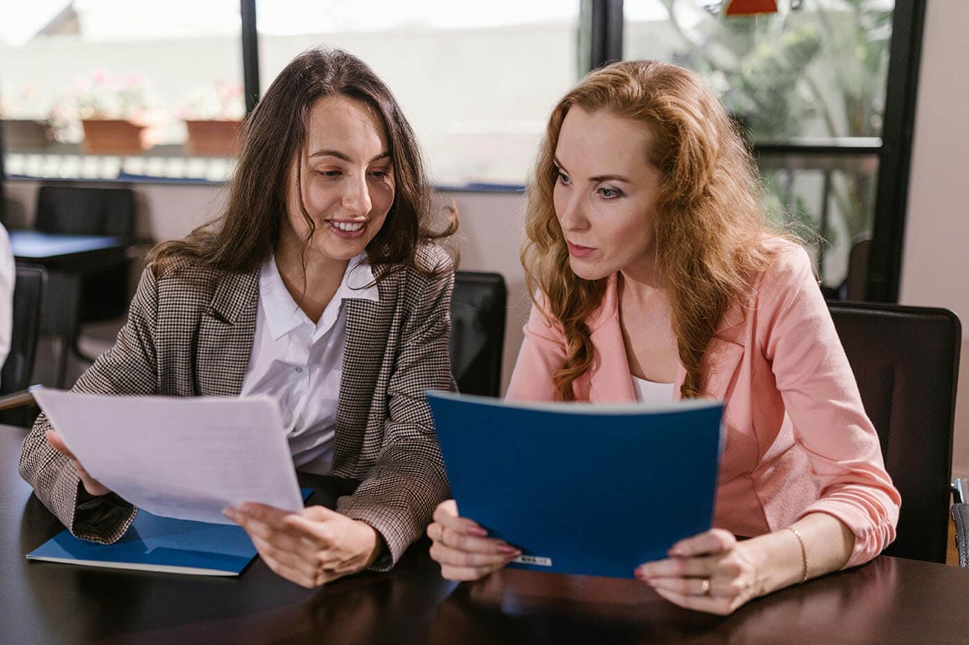 Coaching vs. mentoring concept: Two colleagues meet and review documents