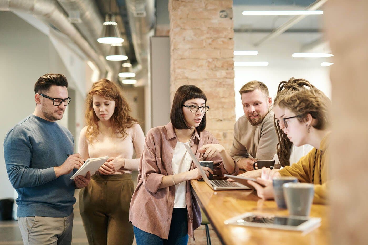 Workplace meeting with six employees, including men and women.